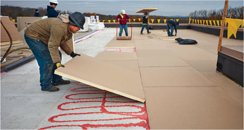 Image of a roofers installing adhered polyiso taper system